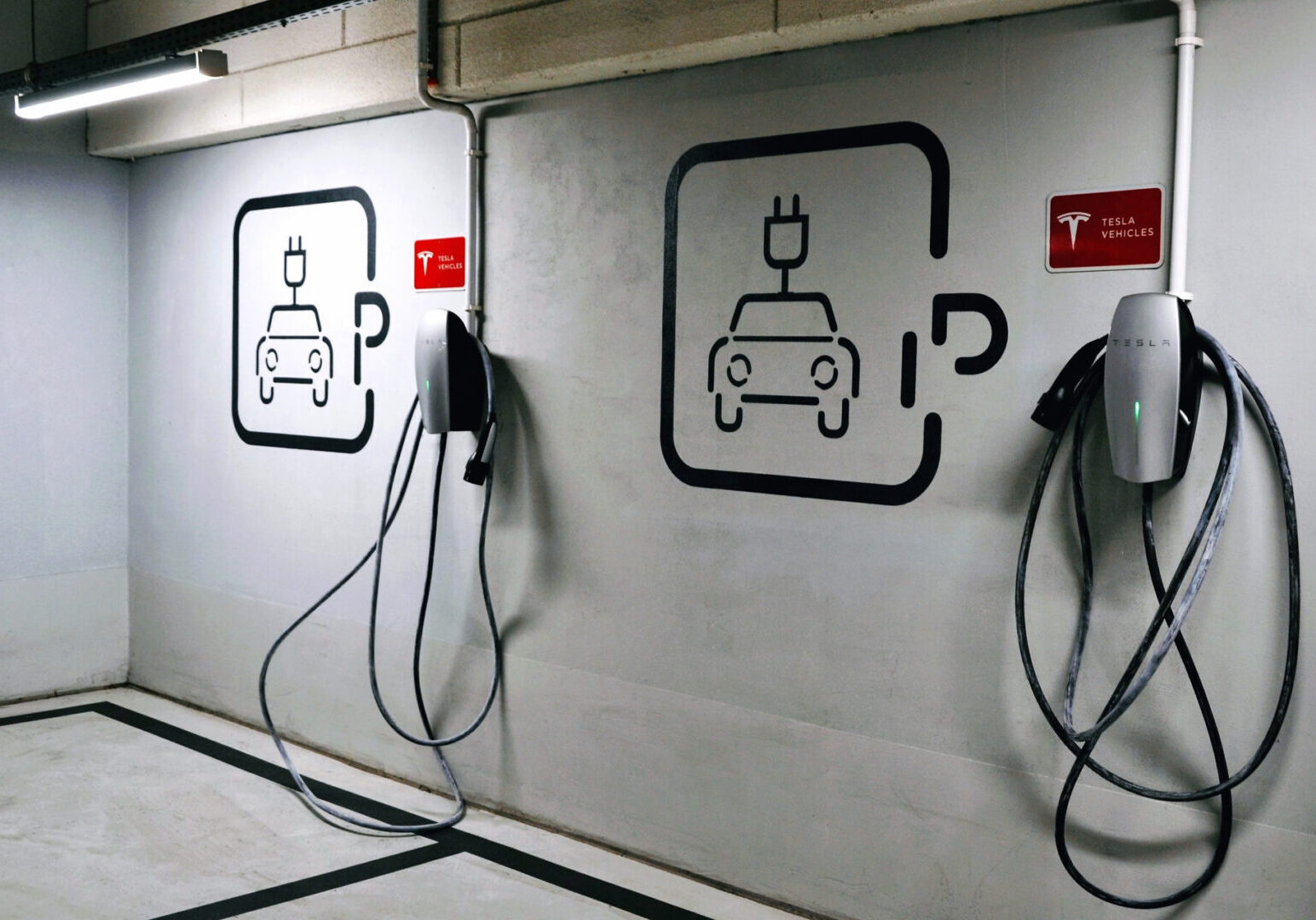A wall with two electric cars charging on it